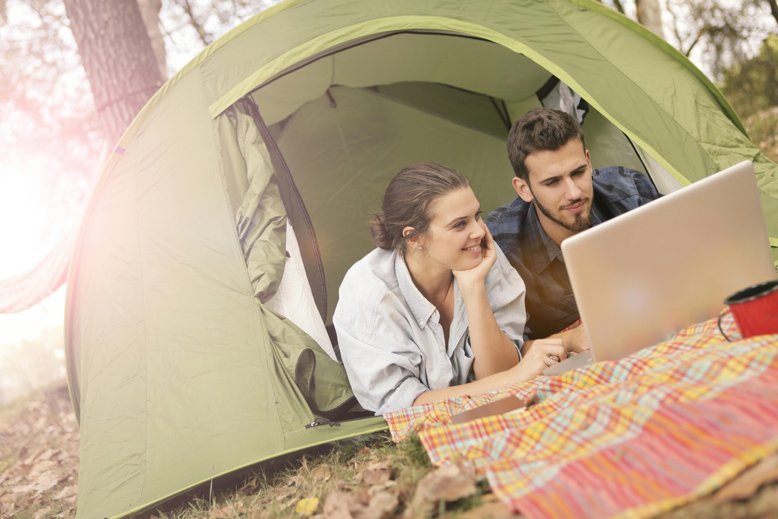 young couple on a campsite looking at a laptop for tourism business