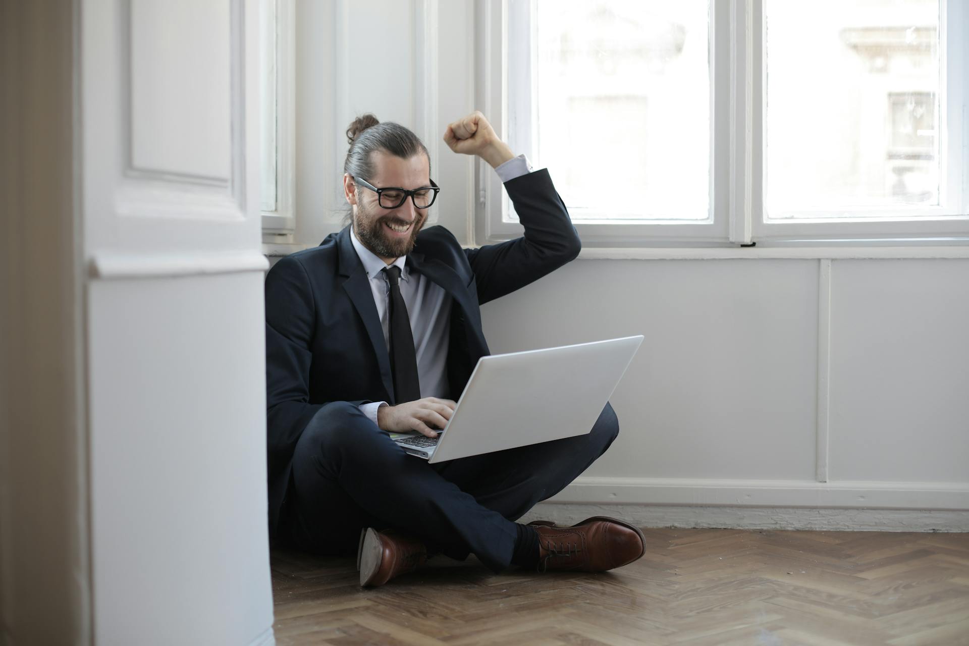 Happy business owner with laptop in a minimalist room suggesting growth from tech audit